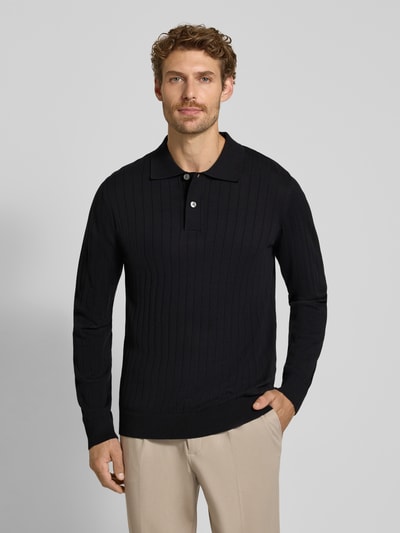 Männermodel trägt schwarzes Regular Fit Poloshirt aus reiner Baumwolle Modell 'TORINO' von Selected; dezente Struktur, Ganzkörperansicht von vorne.