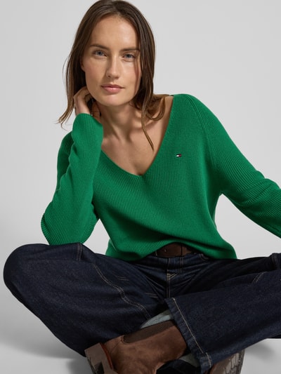 Kobiece model prezentuje zielony Regular Fit Strickpullover aus reiner Baumwolle od Tommy Hilfiger, rippstrick, logo, długi rękaw, unikalny wzór; ujęcie: z przodu, zbliżenie na górną część ciała.