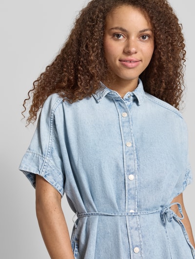 Kobiece model prezentuje Relaxed Fit Jeanskleid aus reiner Baumwolle von Marc O'Polo Denim, tkanina stylizowana na denim, krój relaxed fit, długość mini, wysokie zapięcie, wiązany pasek, kołnierzyk koszulowy, listwa guzikowa, krótki rękaw, materiał: czysta bawełna. Zbliżenie na górną część ciała.