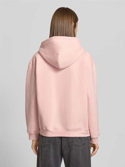 Vrouwenmodel draagt Hoodie met Kapuze van Levi's®, lichtroze, katoen-elastaan, losse pasvorm, ribboorden, kangoeroezak, rugaanzicht.