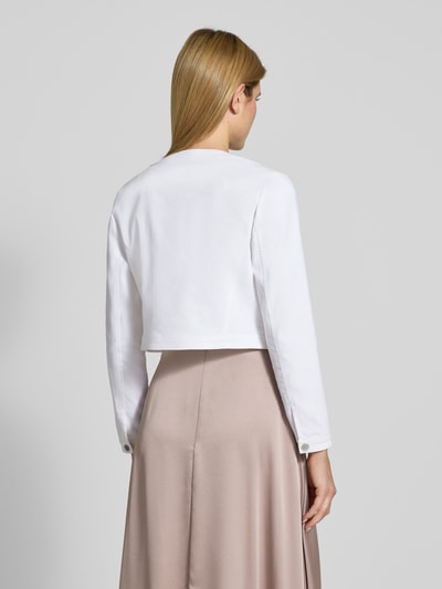 Männermodel trägt Cropped Jacke mit Brusttaschen von SWING, mieszanka bawełny z dodatkiem streczu, krój krótki, otwarty fason, kieszenie na piersi, długość tyłu w rozmiarze 36: 44 cm, widok całej sylwetki z tyłu.