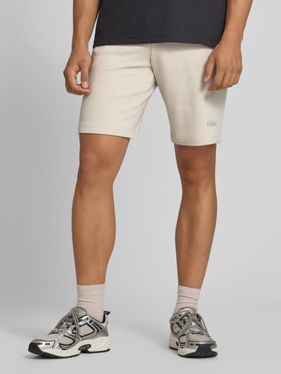 Männermodel trägt Shorts mit Logo und elastischem Bund von PUMA, cremefarben, Baumwoll-Mix, Regular Fit, Nahaufnahme Oberschenkel.