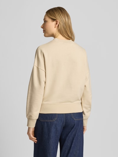 Vrouwenmodel draagt Relaxed Fit Sweatshirt met floralem stitching van Scotch & Soda in beige, puur katoen, ronde hals, elastische boorden, motiefprint, relaxed fit, bloemenmotief, motiefprint, rugaanzicht, dames sweatshirt. Ganzkörperansicht Rückansicht.