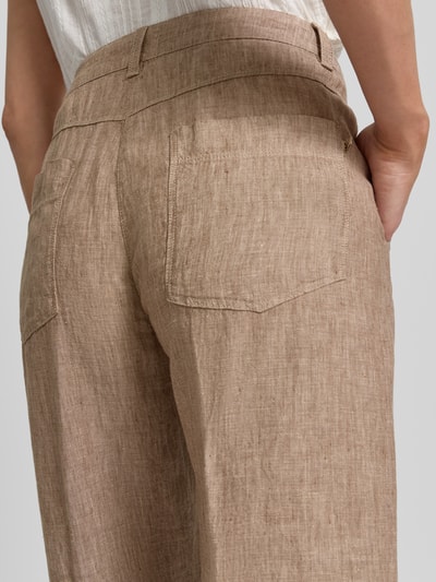 Kobieta nosi Culotte aus Leinen mit Eingrifftaschen Modell 'Nora' od MAC z czystego lnu, krój wide leg fit, detal z logo, francuskie kieszenie, kolor beżowy, tekstura lniana, szerokość w rozmiarze 36: 44 cm, długość nogawki od kroku: 67 cm, zapięcie na guzik i zamek, detal tylnej kieszeni, zbliżenie na biodra.
