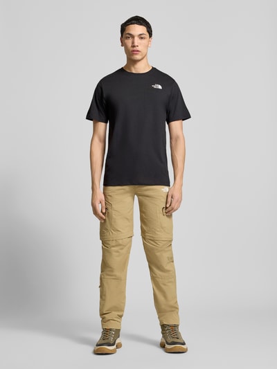 Männermodel trägt T-Shirt mit Logo und Rundhalsausschnitt von The North Face in Schwarz, Regular Fit, Baumwoll-Mix, Ganzkörperansicht von vorne.