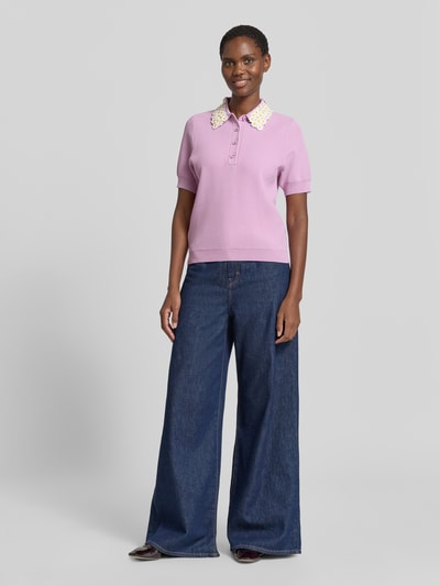 Frauenmodel trägt Regular Fit Poloshirt aus Viskose-Mix Modell 'JAMBER' von Essentiel Antwerp in Flieder mit floraler Kragenstruktur, Ganzkörperansicht von vorne.