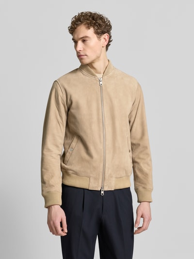 Männermodel trägt Regular Fit Wildlederjacken aus reinem Ziegenleder Modell 'ARCHIVE' von SELECTED HOMME in Beige, College-Kragen, Zweiwege-Reißverschluss, glatte Veloursleder-Textur, gerade geschnitten, gerippte Abschlüsse, seitliche Eingrifftaschen; Ganzkörperansicht von vorne.