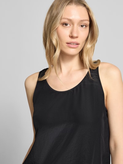 Kobiece modelka nosi Blusenshirt mit Rundhalsausschnitt und Label-Detail od Marc Cain, satyna, krój straight fit, okrągły dekolt, długość tyłu w rozmiarze 36: 52 cm, czarny kolor, lekki połysk, tekstura gładka, zbliżenie na górną część ciała.