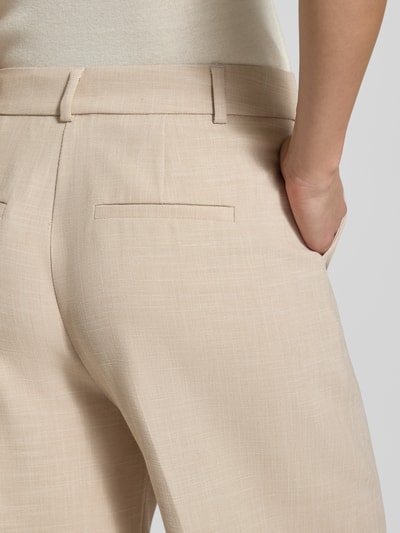 Frauenmodel trägt Relaxed Fit Stoffhose mit Viskose-Anteil und Bügelfalten von Comma, Beige mit Elastischer-Material-Mix, Nahaufnahme Gesäß.