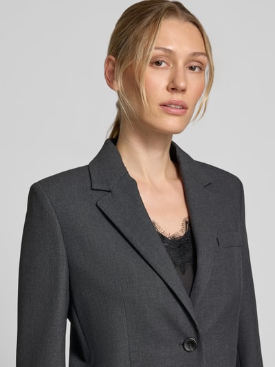 Frauenmodel trägt Blazer mit Viskose-Anteil Modell 'Bergen' von MANGO in Grau, elastischer Stoff, Reverskragen, Nahaufnahme Oberkörper.