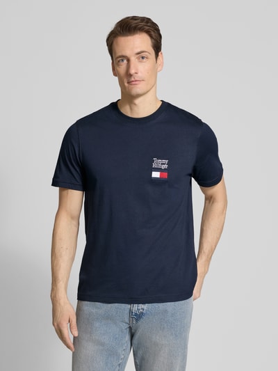 Männermodel trägt Regular Fit T-Shirt aus reiner Baumwolle Modell 'BRAND LOVE TEXT' von Tommy Hilfiger in Dunkelblau, Logo-Stitching, Ganzkörperansicht von vorne.
