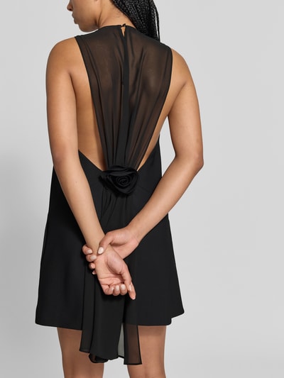 Frauenmodel trägt Relaxed Fit Kleid in Knielänge von ROTATE, elastischer Material-Mix, ärmellos, Rückenteil transparent, Ganzkörperansicht Rückansicht.