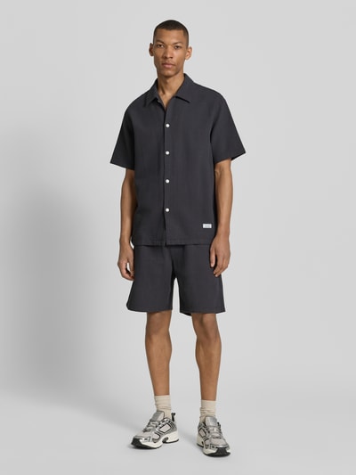 Männermodel trägt Regular Fit Sweatshorts aus reiner Baumwolle von Marc O'Polo Denim, unifarben, Piqué-Textur, Ganzkörperansicht von vorne.