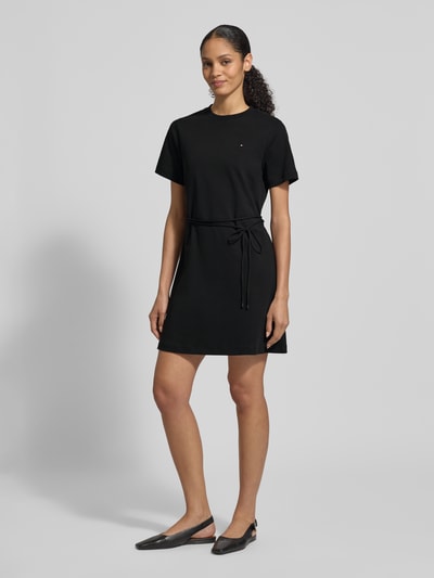 Vrouwenmodel draagt Tailliertes Sweatkleid aus reiner Baumwolle van Tommy Hilfiger, zwart, getailleerde fit, mini lengte, ronde hals, korte mouw, logo-stiksel, ceintuur, rechte zoom, interlock, puur katoen. Volledig lichaam van voren.
