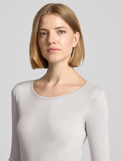 Frauenmodel trägt T-Shirt mit Rundhalsausschnitt und Label-Detail von Marc Cain, Baumwoll-Elasthan-Mix, Slim Fit, Nahaufnahme Oberkörper.