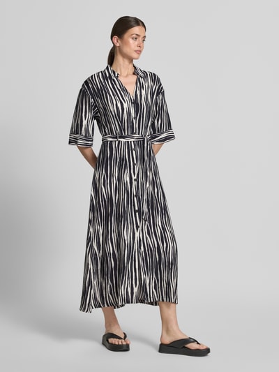 Frauenmodel trägt Hemdblusenkleid aus Viskose-Mix mit Knopfleiste Modell 'Salma' von GUIDO MARIA KRETSCHMER WOMAN, taillierter Schnitt, Midikleid, Hemdblusenkragen, Bindegürtel, abstraktes Streifenmuster in Schwarz und Creme, fließende Textur, Rückenlänge 131 cm, Brustweite 46 cm, Ärmellänge 39 cm, Ganzkörperansicht von vorne.
