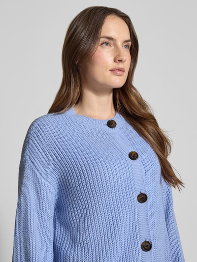 Vrouwenmodel draagt Regular Fit Strickjacke met eenrijige knoopsluiting model 'LEA' van Vero Moda, effen, gebreid materiaal, ronde hals, langemouw, ribboorden. Close-up bovenlichaam.
