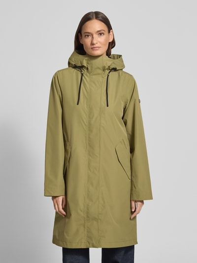 Frauenmodel trägt Parka mit Pattentaschen Modell 'ELINA' von Didriksons in Olivgrün, entspannter Schnitt, Kapuze, Ganzkörperansicht von vorne.