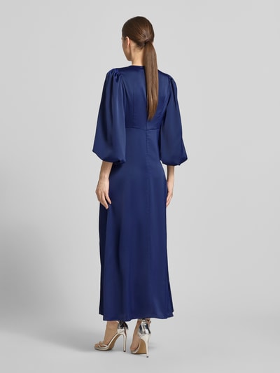Vrouwenmodel draagt Maxikleid met Ballonärmeln Modell 'THEA' van YAS in effen donkerblauw materiaalmix met stretch, getailleerd model, ruglengte bij maat 36: 35 cm, borstwijdte: 32 cm, mouwlengte: 49 cm, Ganzkörperansicht Rückansicht.