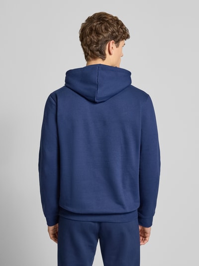 Męski model nosi Hoodie mit Kapuze od adidas Originals w kolorze granatowym, bawełniany miks, luźny krój, długość tyłu 70 cm, rękaw 67 cm, widok całej sylwetki z tyłu.