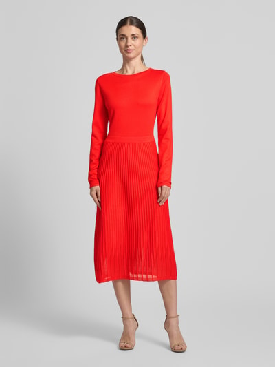 Modelka nosi Tailliertes Strickkleid aus Viskose-Mix od s.Oliver BLACK LABEL, czerwony, krój taliowany, midi, okrągły dekolt, długie rękawy, faktura prążkowana, dzianina z mieszanki wiskozy, widok całej sylwetki z przodu.