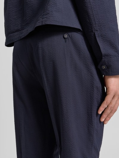 Männermodel trägt Straight Fit stoffen broek van Officine Générale van puur katoen in donkerblauw met stolpplooi, detailaufnahme rugzijde