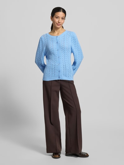 Frauenmodel trägt Strickjacke mit gerippten Abschlüssen Modell 'Clarry' von FREE/QUENT im Regular Fit aus Viskose-Mix in Hellblau, Rundhalsausschnitt und Knopfleiste, kombiniert mit brauner Hose, Ganzkörperansicht von vorne.
