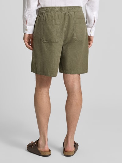 Männermodel trägt Leinenshorts mit elastischem Bund von GAP in Olive, Baumwolle-Leinen-Mix, Loose-Fit, Gesäßtaschen, Ganzkörperansicht Rückansicht.