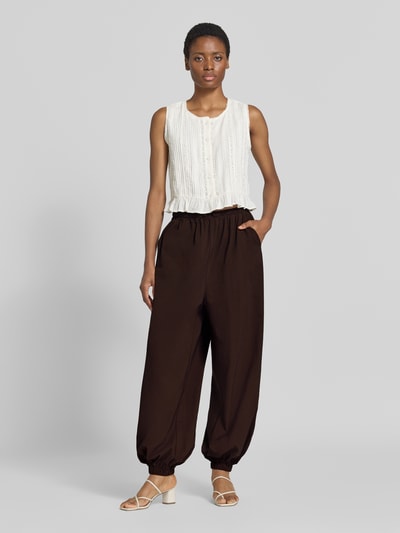 Frauenmodel trägt Balloon Fit Stoffhose aus Viskose-Mix Modell 'Hamy' von FREE/QUENT in Dunkelbraun, elastischer Bund, seitliche Eingrifftaschen, lässige Form, Ganzkörperansicht von vorne.