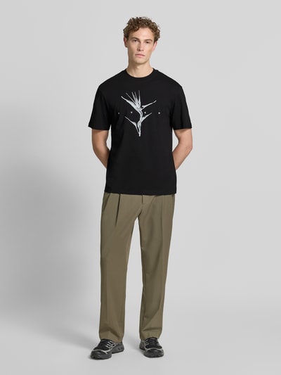 Männermodel trägt Relaxed Fit T-Shirt aus reiner Baumwolle Modell 'DARISE' von HUGO in Schwarz, mit Print, Ganzkörperansicht von vorne, Herren T-Shirt.
