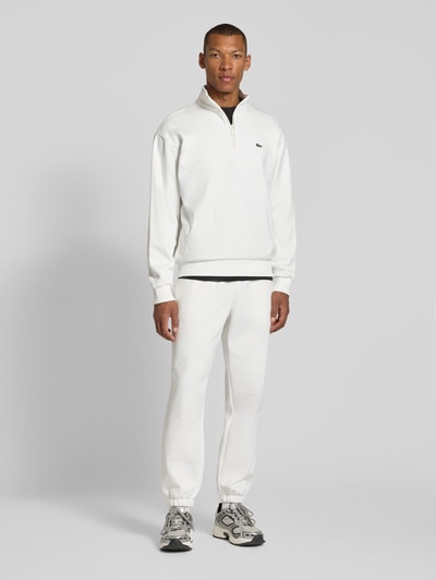Männermodel trägt Regular Fit Sweathose aus Baumwoll-Mix von Lacoste in Weiß, lockere Passform, glatte Textur, Ganzkörperansicht von vorne, Herren Sweathose von Lacoste.