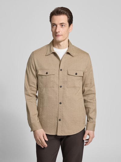 Männermodel trägt Regular Fit Hemdjacke mit Eingrifftaschen von Tiger Of Sweden aus reiner Baumwolle, Kentkragen, Brusttaschen, Ganzkörperansicht von vorne. Rückenlänge bei Größe M: 76 cm.
