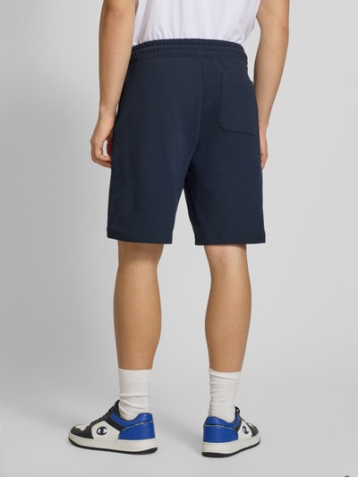 Männermodel trägt Regular Fit Sweatshorts aus reiner Baumwolle Modell 'NASENSIO' von Hugo Blue, Optik: Unifarben, Ganzkörperansicht Rückansicht.