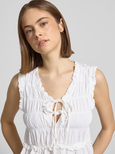 Frauenmodel trägt Regular Fit Blusentop aus Viskose-Leinen-Mix Modell 'GOA' von Only, Optik: Unifarben, Rüschenkragen, dezent gesmokt, V-Ausschnitt mit Schnürung, Ärmelform: Ohne Ärmel, Materialverarbeitung: Smok Flammgarn, Nahaufnahme Oberkörper.