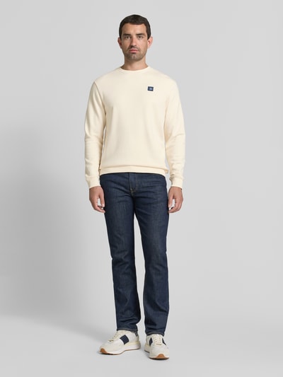 Männermodel trägt Sweatshirt mit Label-Badge und Rundhalsausschnitt van Scotch & Soda in puur katoen, regular fit, ruglengte maat M 71 cm, mouwlengte maat M 68 cm, crèmekleurig, gladde structuur, Ganzkörperansicht von vorne