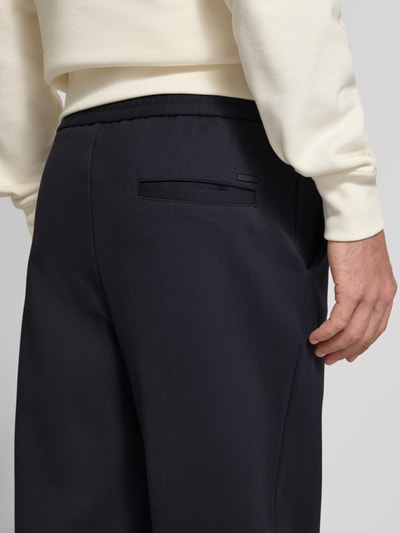 Mannenmodel draagt donkerblauwe straight fit broek van viscosemix Model 'Karl' van JACK & JONES, detailopname achterkant, heren broek, elastische band, bandwijdte bij maat M 41 cm, binnenbeenlengte bij maat M 79 cm.