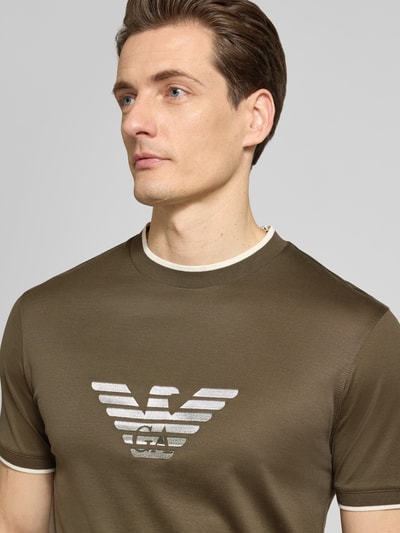 Männermodel trägt Regular Fit T-Shirt mit Logo-Stitching von Emporio Armani in Olivgrün mit Rundhalsausschnitt, Nahaufnahme Oberkörper.