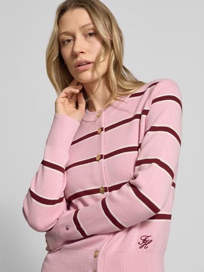 Modelka nosi Regular Fit Strickjacke aus reiner Baumwolle von Tommy Hilfiger, wzór w paski, wyhaftowane logo, drobny splot, bawełna, efekt: wzór na całej powierzchni, okrągły dekolt, listwa guzikowa, długi rękaw; zbliżenie na górną część ciała, widok z przodu.
