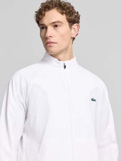 Männermodel trägt Regular Fit Trainingsanzug mit Logo-Detail von Lacoste Sport in Weiß, Sweat-Material, Nahaufnahme Oberkörper.