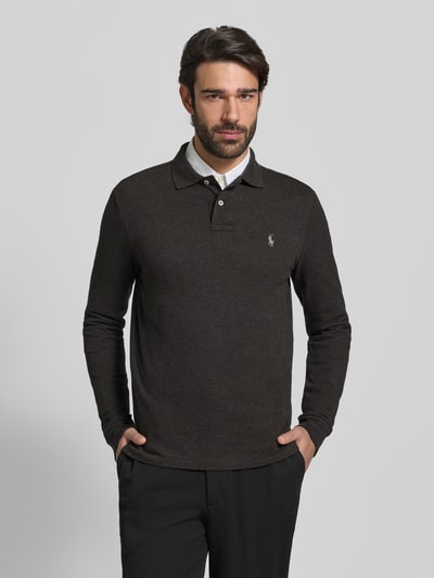 Männermodel trägt Poloshirt mit Label-Stitching von Polo Ralph Lauren in dunklem Braun, reine Baumwolle, Regular Fit, Ganzkörperansicht von vorne.