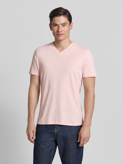 Męski model nosi Regular Fit T-Shirt aus reiner Baumwolle von s.Oliver RED LABEL w kolorze jasnoróżowym, gładka faktura, krój regular fit, V-dekolt, krótki rękaw, jersey z czystej bawełny; całopostaciowy widok z przodu.
