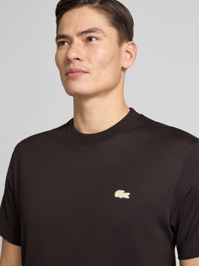 Męski model nosi Regular Fit T-Shirt aus reiner Baumwolle Modell 'LOURD' od Lacoste, gładki czarny, logo na piersi, bawełna, zbliżenie górnej części ciała.