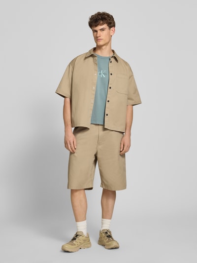Männermodel trägt Relaxed Fit T-Shirt aus reiner Baumwolle von Calvin Klein Jeans in Optik: Unifarben mit Label-Print, Ganzkörperansicht von vorne.