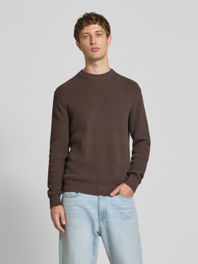 Männermodel trägt Slim Fit Pullover aus reiner Baumwolle in Strick-Optik von Replay in Braun, Rundhalsausschnitt, Logo-Stitching, Ganzkörperansicht von vorne.