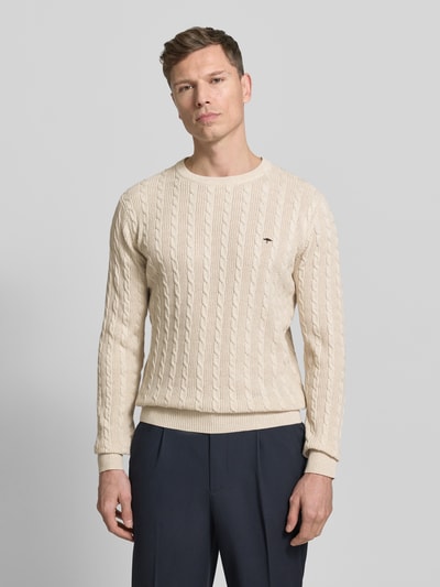 Männermodel trägt Strickpullover mit Zopfmuster und Label-Stitching von Fynch-Hatton in Beige aus reiner Baumwolle, Slim-Fit, Nahaufnahme Oberkörper.