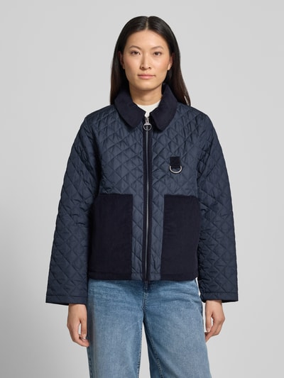 Kobiece model prezentuje granatową kurtkę pikowaną Regular Fit Steppjacke mit aufgesetzten Seitentaschen Modell 'AYLESBY' od Barbour, damska kurtka pikowana, prosty fason, prostokątne kieszenie, tekstura pikowania, Ganzkörperansicht von vorne.