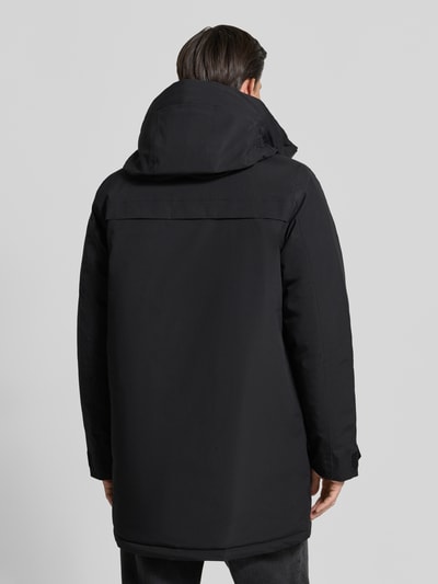 Männermodel trägt Parka mit Kapuze und Pattentaschen Modell 'AIDEN' von Didriksons, schwarze glatte Oberfläche, Ganzkörperansicht Rückansicht. Regular Fit, verdeckter Reißverschluss, Rückenlänge 95 cm, Schulterbreite 47 cm, Brustweite 55 cm, Ärmellänge 68 cm.