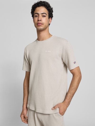 Männermodel trägt T-Shirt mit Strukturmuster und Label-Stitchings von CHAMPION in Beige, Baumwoll-Mix, Regular Fit, Nahaufnahme Oberkörper.