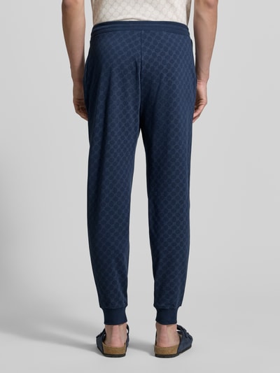 Männermodel trägt Sweatpants mit Logo-Muster und elastischem Bund von JOOP! Collection aus reiner Baumwolle im Regular-Fit, Ganzkörperansicht Rückansicht.