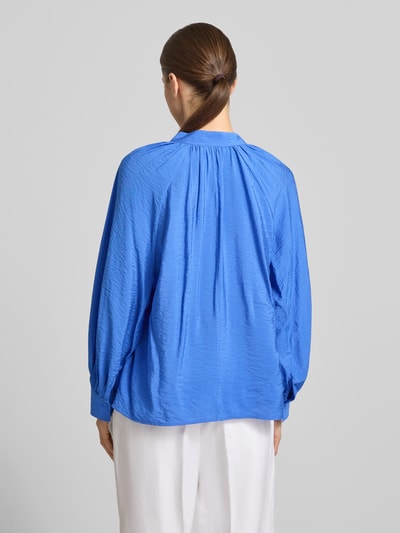 Frauenmodel trägt Bluse aus Viskose-Mix mit Serafino-Ausschnitt von Christian Berg Woman in Blau, lockere Passform, Sportmanschetten, Rückenlänge 61 cm, Ärmellänge 64 cm, Ganzkörperansicht Rückansicht.